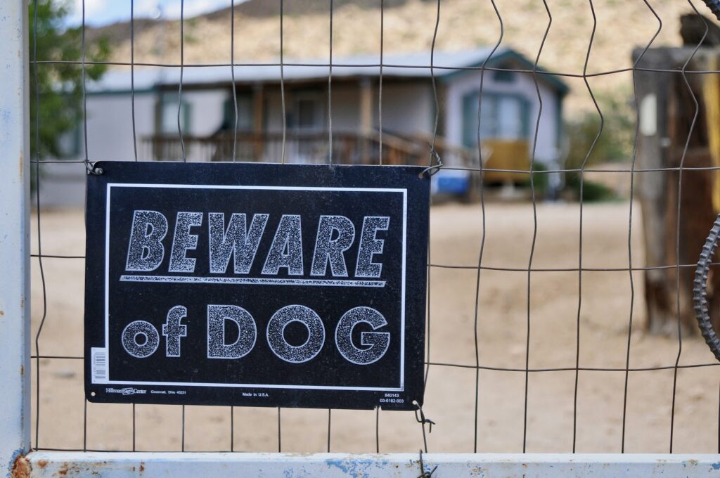 "Beware of Dog" sign hung on wire fence in front of home.
