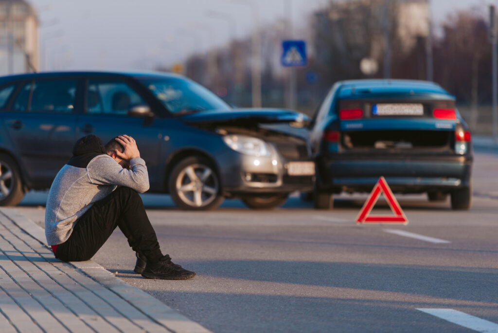 A man sitting with his head in his hands in front of a two-car accident in Hobbs.